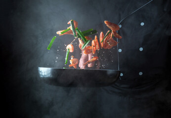 Professional chef prepares shrimp with herbs. Cooking seafood, healthy vegetarian food and food on a dark background.