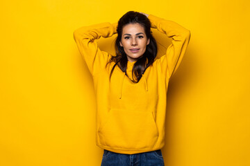 Young beautiful woman holding her hands on the head with happy exited emotional face isolated over yellow background