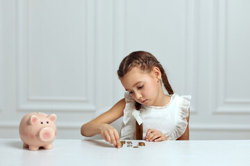 Little child girl with piggy bank at home