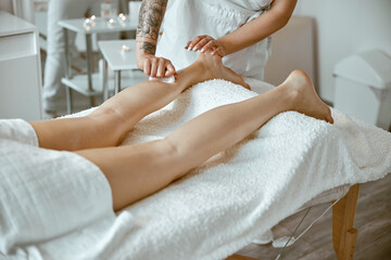 Fototapeta na wymiar Massagist woman is doing professional leg massage in modern salon