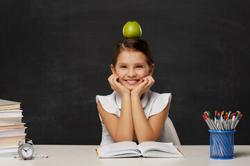 little child girl studying in the classroom on background of blackboard