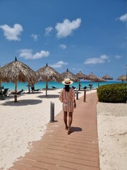 Aruba Caribbean couple man and woman mid age on vacation on the beach with palm trees on the beach, woman girl mid age walking on beach white sand Aruba shore © Fokke Baarssen