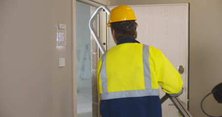 Close up of professional builder in uniform walking in renovating apartment