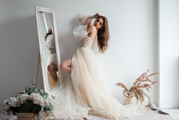 Attractive girl in a beige dress poses in the studio loft