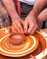 A male Potter works on a Potter's wheel, making a vase.