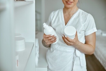 beautiful happy caucasian female masseur is posing in white minimalistic modern treatment salon