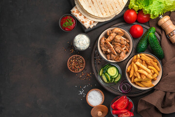 Ingredients for shawarma, burritos, gyros, or a full meal of French fries, fried chicken and vegetables. Top view, copy space.