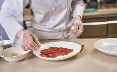 Person carefully picking beef slices from plate