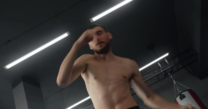 Mixed martial art fighter does shadow boxing, fighter man is fighting with shadow, kickboxer training strikes in gym, 4k 60p Prores HQ