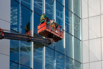 Washing the windows of a skyscraper. Workers in the cradle wash the windows of the building....