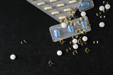 medical pills in packaging and scattered on the table on a dark gray background, top view, empty...