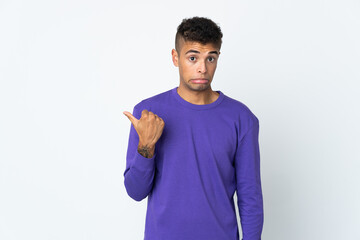 Young brazilian man isolated on white background unhappy and pointing to the side