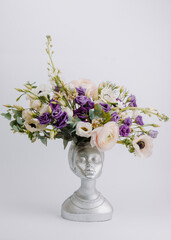 Woman face in the shape of a vase for flowers with Anemone eustoma ranunculus.