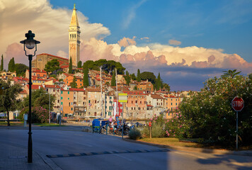 Rovinj, Istria, Croatia. Sunset in medieval old village town of Rovigno, colorful houses and ancient tower during morning sunrise. Picturesque scenic sky with clouds and street lamp by the road.