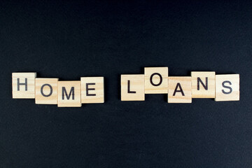 HOME LOAN - word composed fromwooden blocks letters on black background, copy space for ad text.