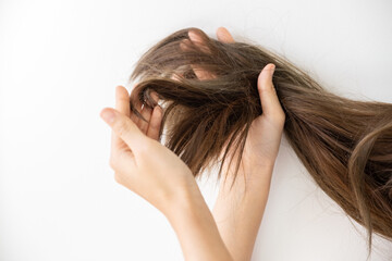 Close up hand holding dry damaged hair problem in white bathroom background.