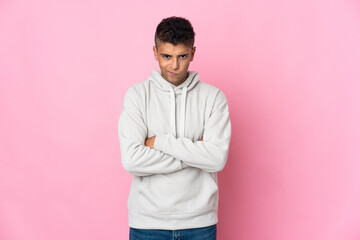 Young Brazilian man isolated on pink background with unhappy expression