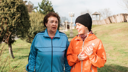 International Day of Older Persons. Portraits of happy a grandmother with an adult granddaughter walking in the park and talking