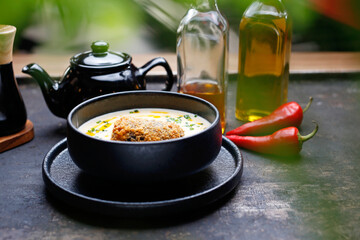 
Creamy soup, a warming dish in a ceramic bowl on a dark background.