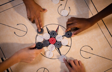 Top view of multiethnic Kids hands arranging carrom board game coins for playing match - Concept of leisure activities, teamwork, cooperation, diversity and success.