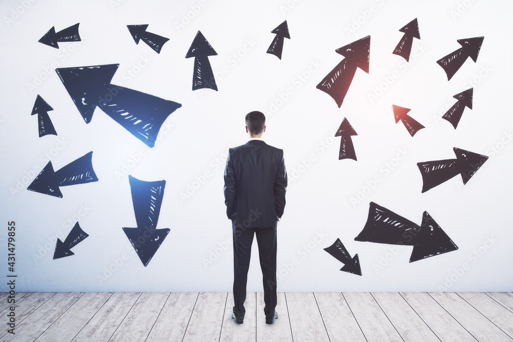 Poster Businessman standing puzzled in front of a wall with multiple black arrows pointed in different directions. Decision making and career pathway concept