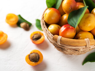 Ripe apricots in a wicker wooden basket on a white stone table