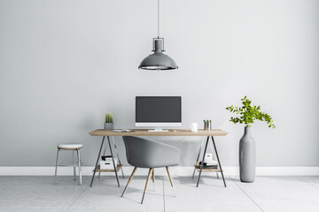Stylish work place interior design in sunny home room with grey lamp, chair, vase and wooden table