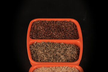 Cumin and flax have fallen into an orange bowl,indian spice caraway and flex seeds