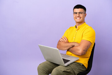 Young man sitting on a chair with laptop keeping the arms crossed in frontal position