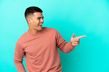 Young handsome man over isolated blue background pointing finger to the side and presenting a product