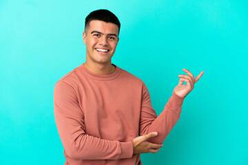 Young handsome man over isolated blue background extending hands to the side for inviting to come