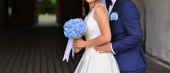 bride and groom together holding a blue flower bouquet - Powered by Adobe