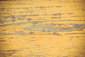The texture of old yellow paint on a wooden board