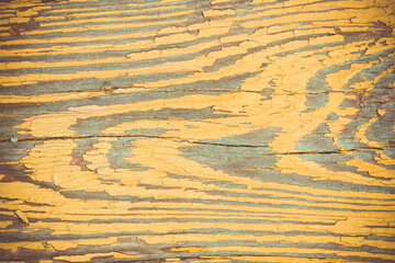 The texture of old yellow paint on a wooden board