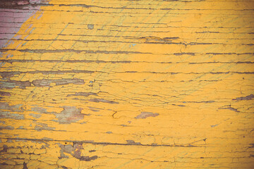 The texture of old yellow paint on a wooden board