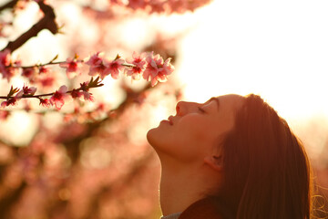 Woman silhouette smelling flowers at sunset