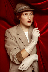 Studio portrait of young fashion model with ginger hair and blue eyes in retro style trendy clothes...
