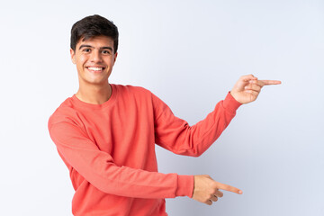 Handsome man over isolated blue background pointing finger to the side and presenting a product