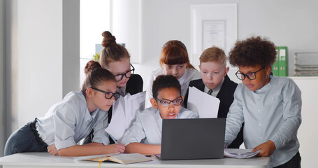 Kids office colleagues looking at laptop discussing work together in conference room at office