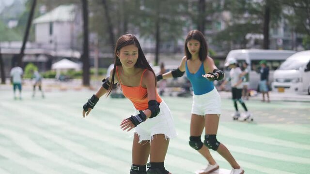 4K Attractive Asian woman skateboarding with girl friends at skate park by the beach in summer day. Happy female friendship enjoy outdoor lifestyle activity play extreme sport surf skateboard together