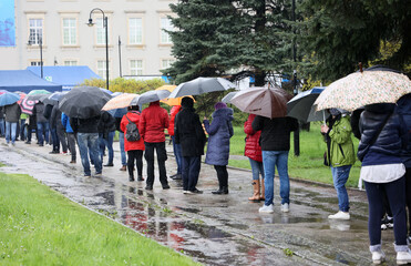 Ludzie pod parasolami czekają w kolejce do mobilnego punktu szczepień we Wrocławiu.  - obrazy, fototapety, plakaty