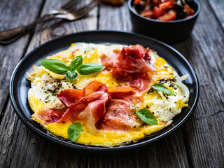 Breakfast - scrambled eggs with serrano ham  and vegetable salad on wooden table
