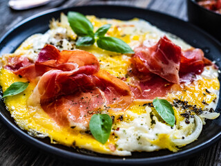 Breakfast - scrambled eggs with serrano ham  and vegetable salad on wooden table
