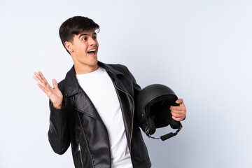 Man with a motorcycle helmet over isolated blue background with surprise facial expression