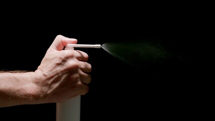 Human Hand Sprays Throat Flu Spray From a Dispenser on a black background