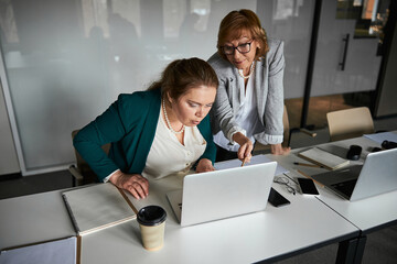 Worker staring at laptop with boss pointing pencil to screen