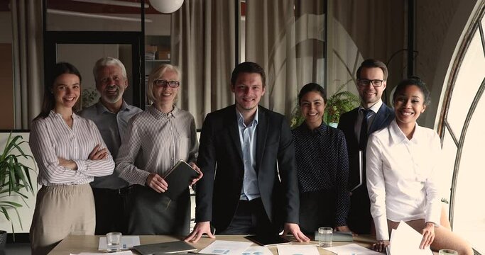 Skilled happy confident male ceo executive manager team leader posing in modern office with smiling friendly multiracial old young colleagues, diverse community unity, professional career concept.