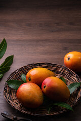Mango. Fresh mango fruit on a bamboo sieve over dark wooden table background.
