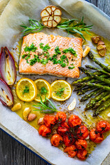Sheet pan dinner - roasted salmon steak with asparagus, lemon ,rosemary, tomatoes, onion and garlic...