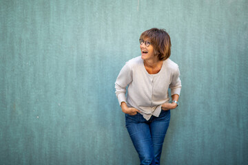 happy woman leaning against wall and laughing